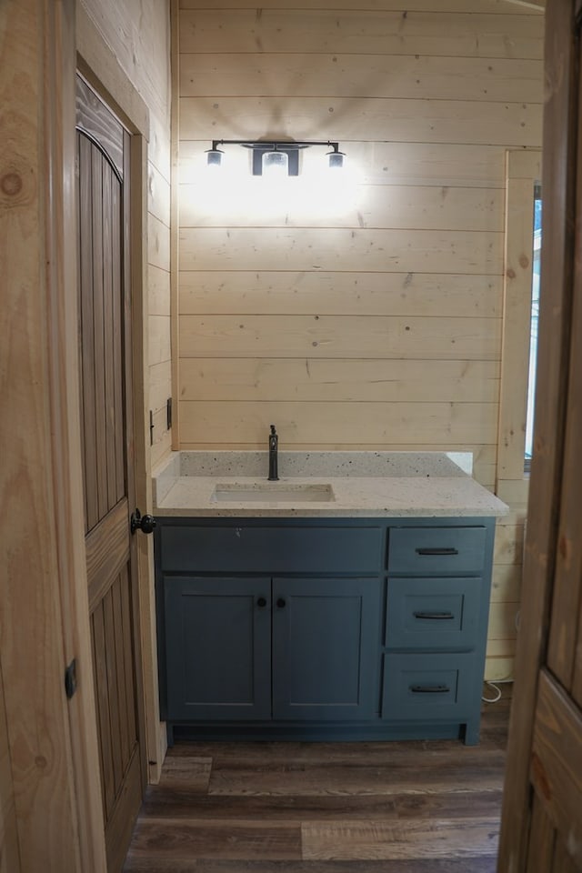 bathroom featuring vanity, wooden walls, and wood-type flooring