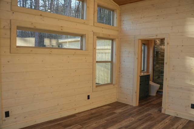 unfurnished room with dark wood-type flooring and wood walls