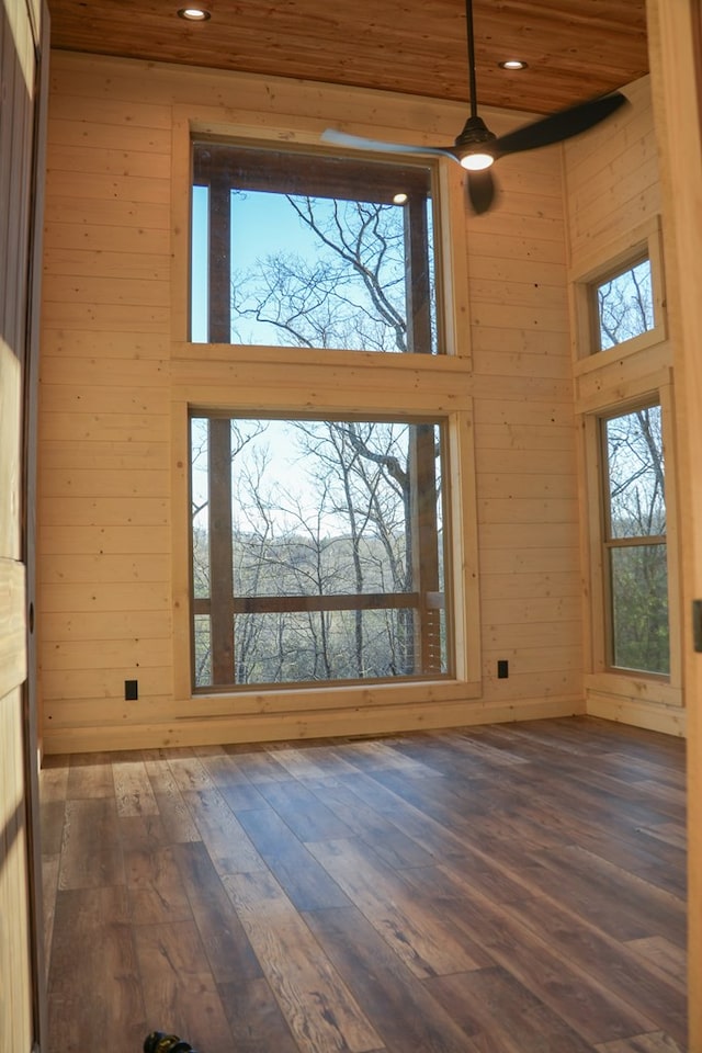 interior space with a high ceiling, dark wood-type flooring, and wood walls