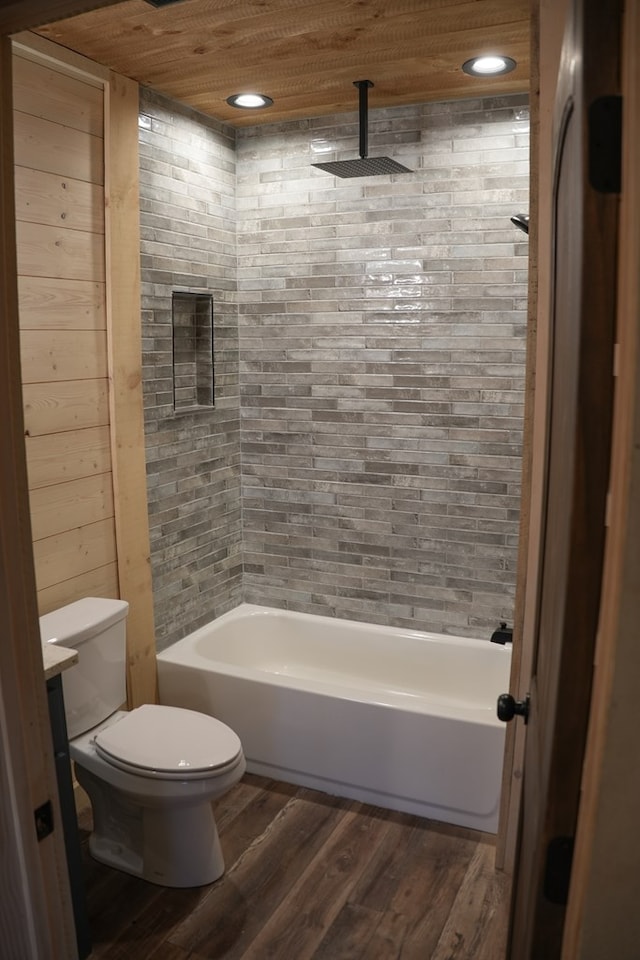 bathroom featuring tiled shower / bath combo, wood-type flooring, wooden ceiling, toilet, and wood walls