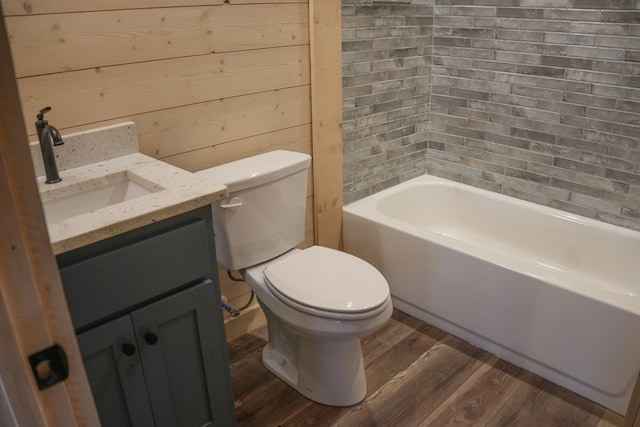 bathroom featuring toilet, wood walls, vanity, hardwood / wood-style flooring, and a washtub