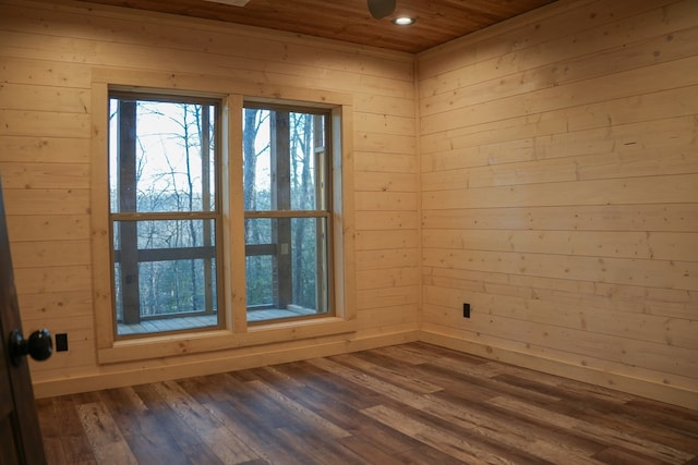 unfurnished room with ceiling fan, wooden ceiling, dark hardwood / wood-style floors, and wood walls