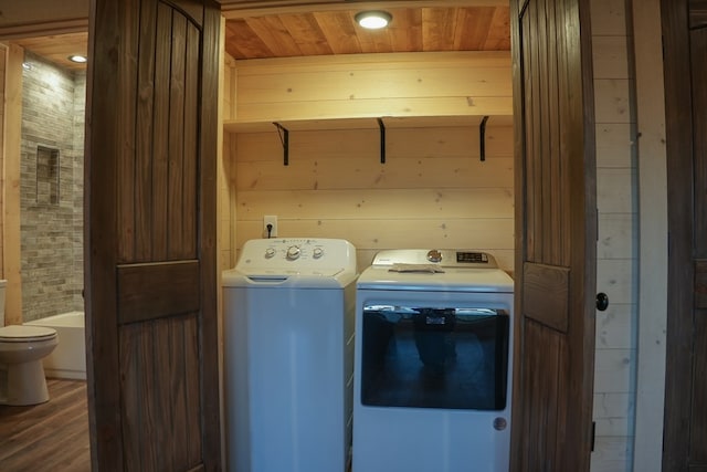 clothes washing area with wooden ceiling, dark hardwood / wood-style floors, washing machine and clothes dryer, and wood walls