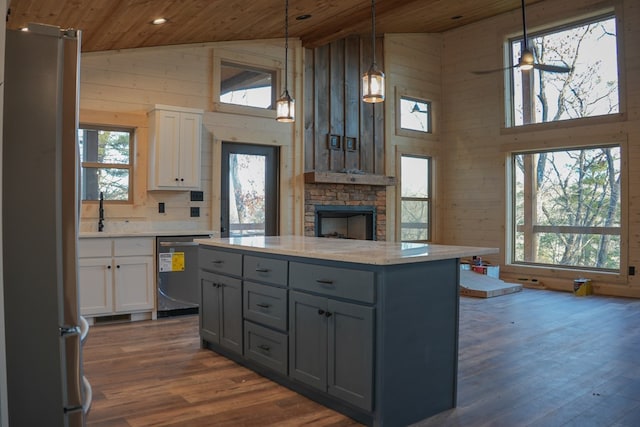 kitchen with stainless steel appliances, wooden walls, hanging light fixtures, and wooden ceiling