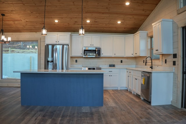 kitchen featuring lofted ceiling, a kitchen island, pendant lighting, stainless steel appliances, and white cabinets