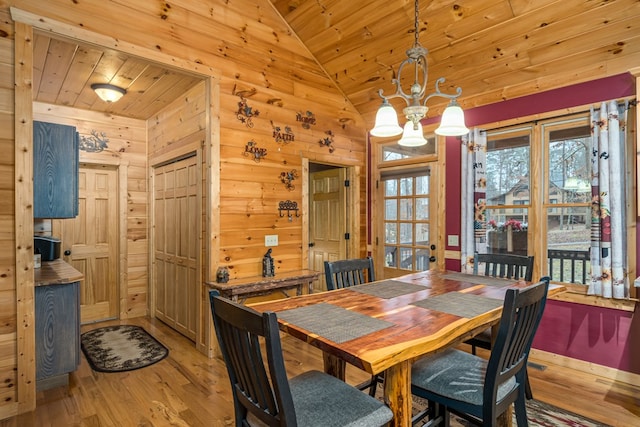 dining room featuring wood walls, vaulted ceiling, wooden ceiling, hardwood / wood-style floors, and a chandelier