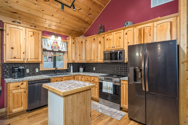 kitchen with stainless steel appliances, a center island, light hardwood / wood-style flooring, sink, and backsplash