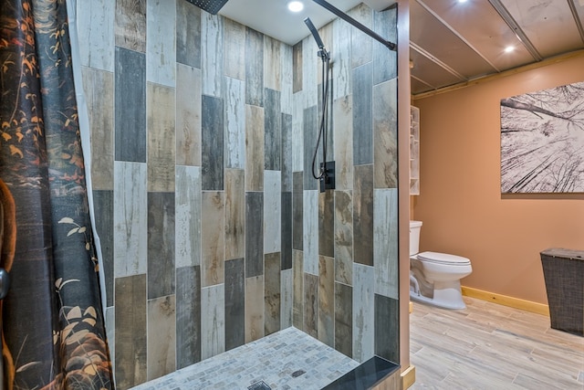 bathroom with a tile shower, toilet, and hardwood / wood-style floors