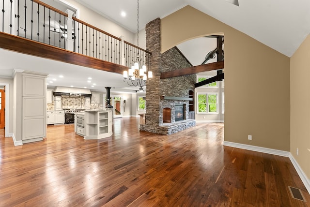 802 Old Mill Trl, Ball Ground, GA 30107 - unfurnished living room featuring high vaulted ceiling, light wood-style floors, baseboards, a chandelier, and arched walkways