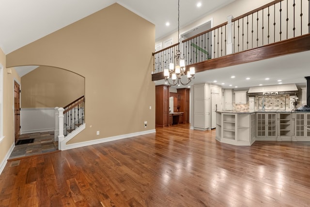 802 Old Mill Trl, Ball Ground, GA 30107 - unfurnished living room featuring a towering ceiling, stairway, dark wood-style flooring, arched walkways, and baseboards