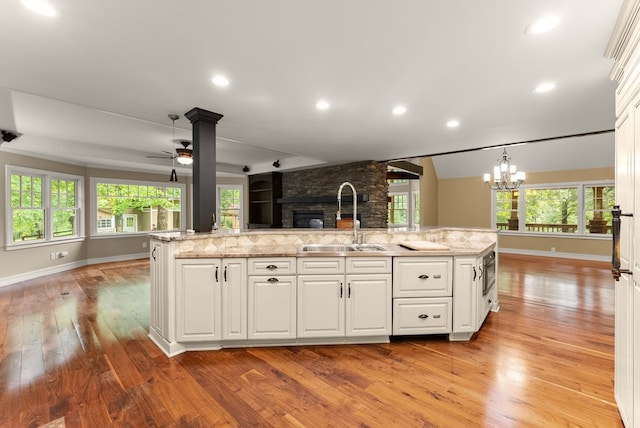 802 Old Mill Trl, Ball Ground, GA 30107 - kitchen featuring open floor plan, a sink, a fireplace, light wood-style flooring, and ceiling fan