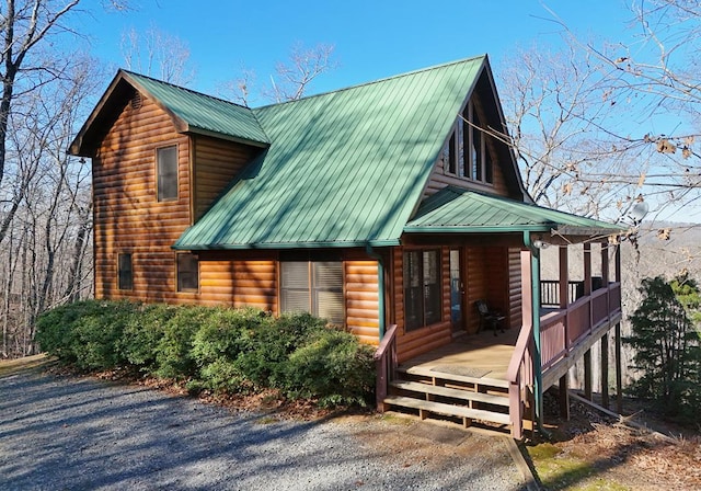 view of side of property featuring faux log siding, a porch, and metal roof