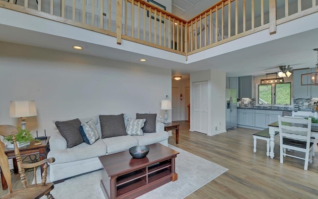 living room with light hardwood / wood-style flooring, a high ceiling, and ceiling fan