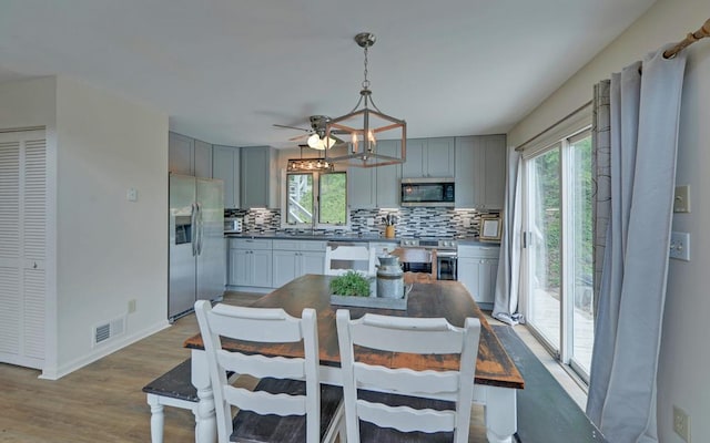 dining area with light wood-type flooring, sink, ceiling fan, and plenty of natural light