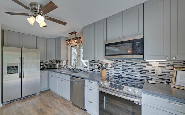 kitchen featuring ceiling fan, sink, tasteful backsplash, appliances with stainless steel finishes, and light wood-type flooring