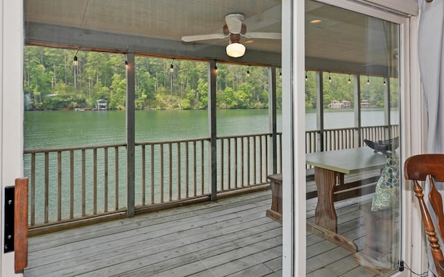 unfurnished sunroom featuring a healthy amount of sunlight, a water view, and ceiling fan