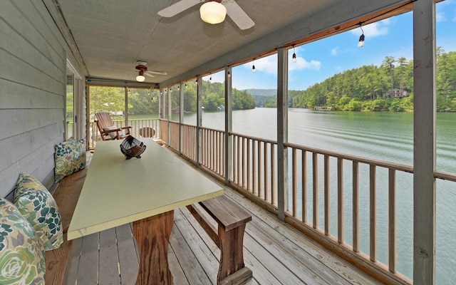 sunroom / solarium with ceiling fan and a water view