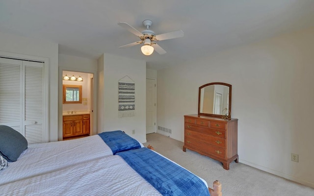 bedroom featuring ceiling fan, connected bathroom, sink, a closet, and light carpet