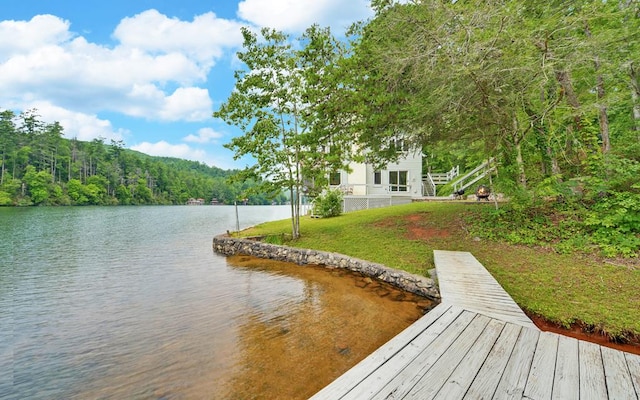 view of dock featuring a water view and a yard