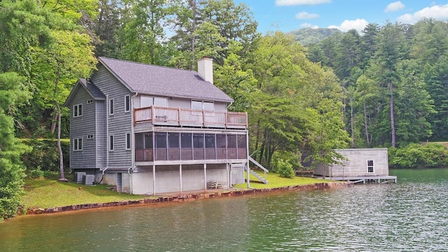 rear view of house with cooling unit, a yard, and a deck with water view