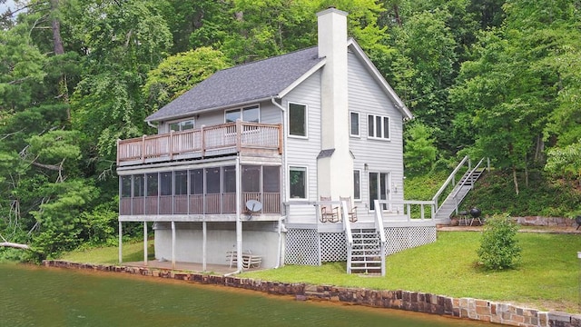 rear view of house with a lawn, a sunroom, and a deck with water view