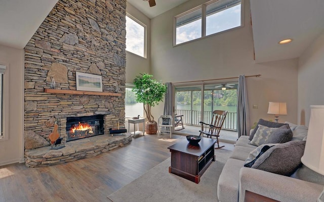 living room featuring wood-type flooring, a high ceiling, plenty of natural light, and a fireplace