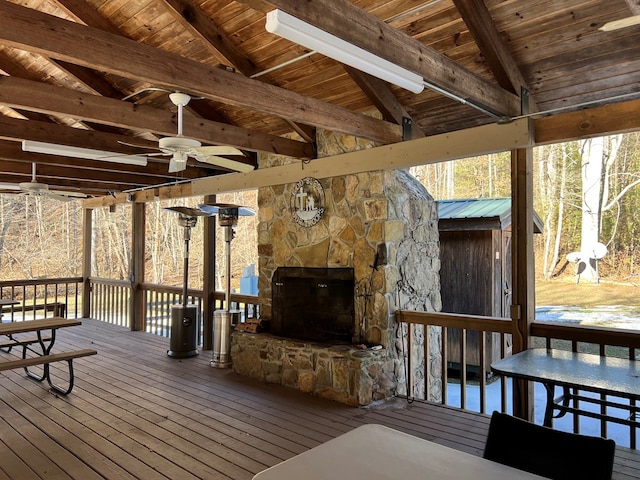 wooden terrace with ceiling fan and a stone fireplace