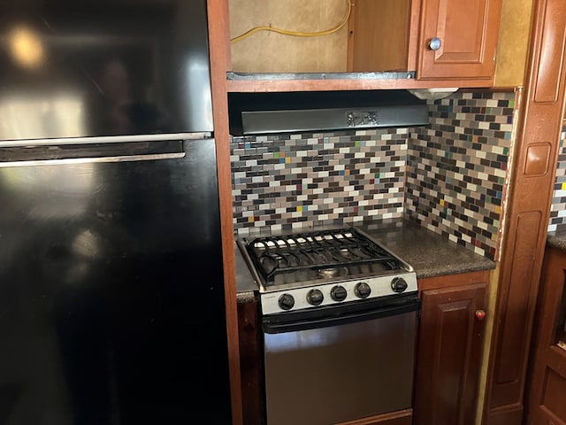 kitchen featuring black fridge, backsplash, and gas stove