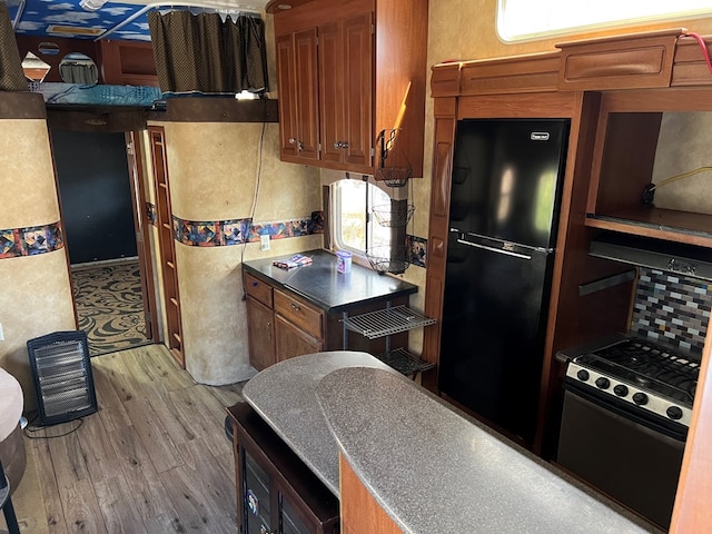 kitchen with black fridge, light hardwood / wood-style flooring, and range