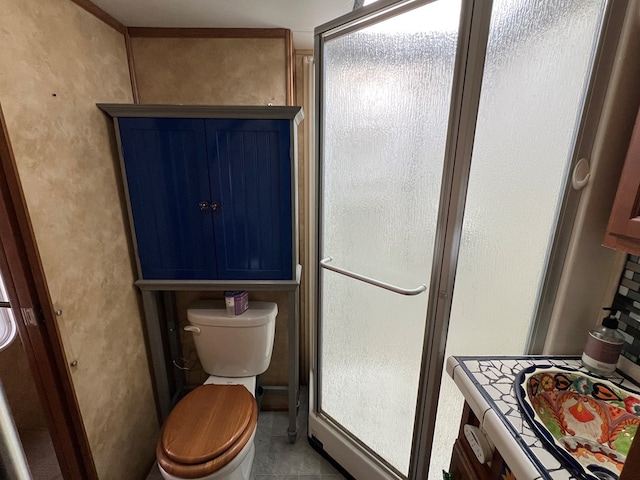 bathroom with toilet, tile patterned flooring, and a shower with door