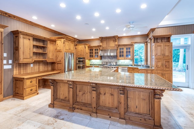 kitchen with a breakfast bar, a spacious island, ceiling fan, ornamental molding, and stainless steel appliances