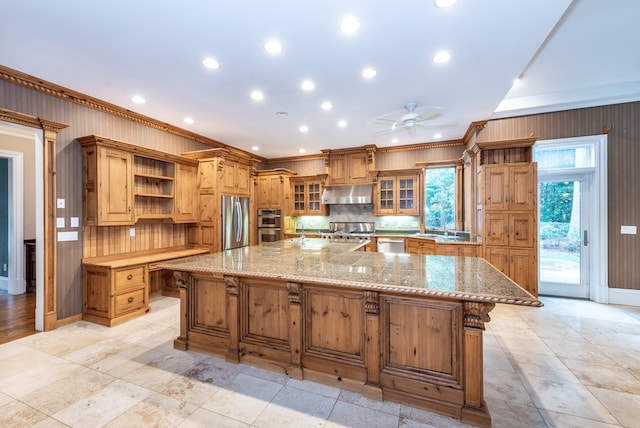 kitchen featuring ceiling fan, stainless steel appliances, a spacious island, decorative backsplash, and ornamental molding