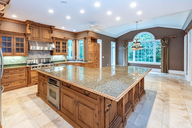 kitchen featuring a large island, ornamental molding, appliances with stainless steel finishes, and vaulted ceiling