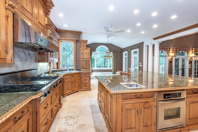 kitchen featuring ornate columns, a kitchen island with sink, sink, stainless steel gas stovetop, and lofted ceiling