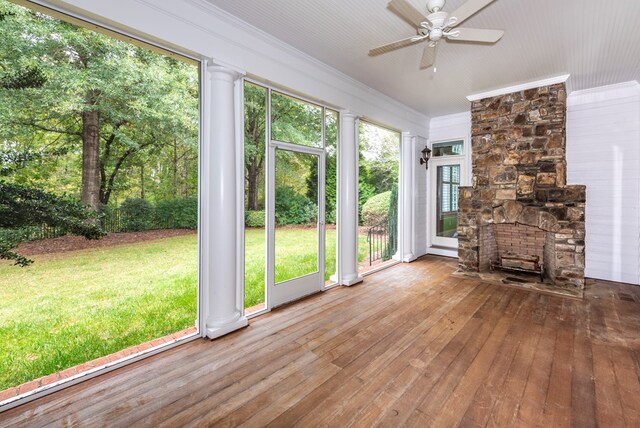 unfurnished sunroom featuring ceiling fan and a fireplace