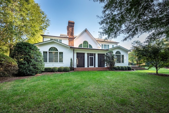 back of house with a sunroom and a lawn