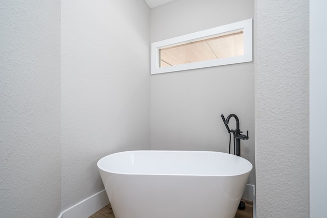 538 Mountain Laurel Rdg, Mineral Bluff, GA 30559 - bathroom with a textured wall, a freestanding bath, wood finished floors, and baseboards