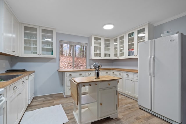 kitchen featuring butcher block counters, light hardwood / wood-style flooring, ornamental molding, white appliances, and white cabinets