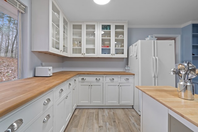 kitchen featuring white cabinetry, crown molding, light wood-type flooring, and white refrigerator