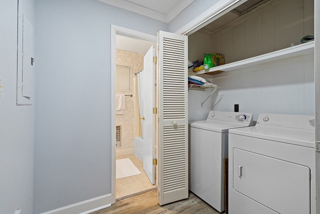 laundry area with ornamental molding, washer and clothes dryer, light hardwood / wood-style flooring, and electric panel