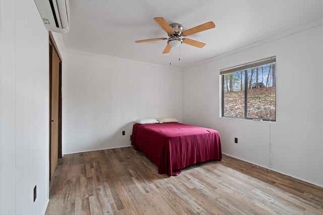 bedroom featuring crown molding, ceiling fan, wood-type flooring, and an AC wall unit