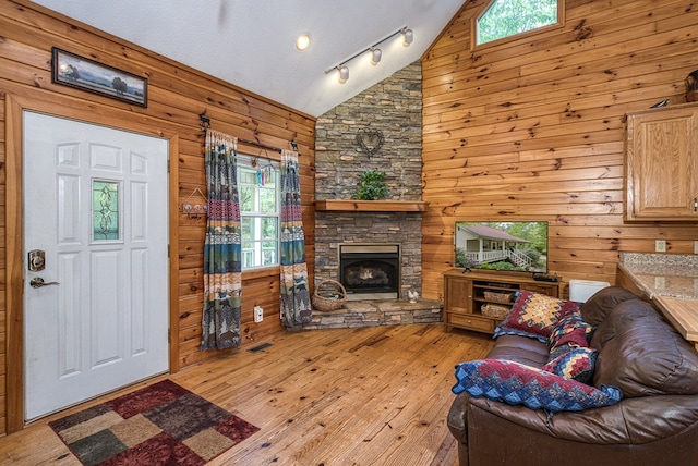 45 8 Point Trl, Blairsville, GA 30512 - living room featuring a stone fireplace, visible vents, high vaulted ceiling, wooden walls, and light wood-style floors