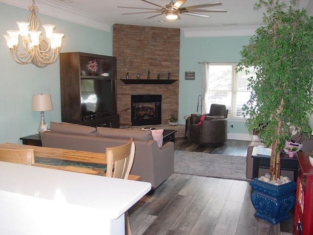 living room with ceiling fan with notable chandelier, hardwood / wood-style flooring, a fireplace, and crown molding