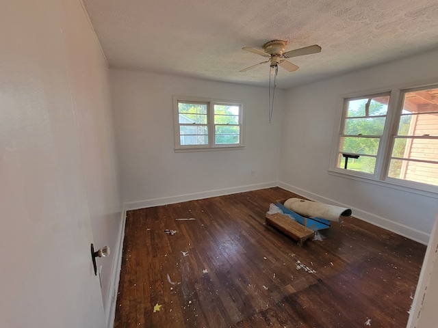 empty room featuring ceiling fan, a wealth of natural light, a textured ceiling, and dark hardwood / wood-style flooring