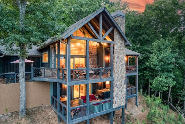 back of property with roof with shingles, a chimney, and a balcony