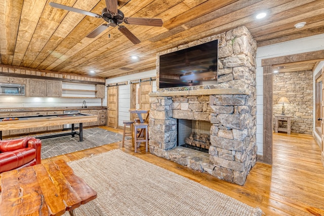 living room with light wood-style floors, recessed lighting, a barn door, wood ceiling, and a ceiling fan