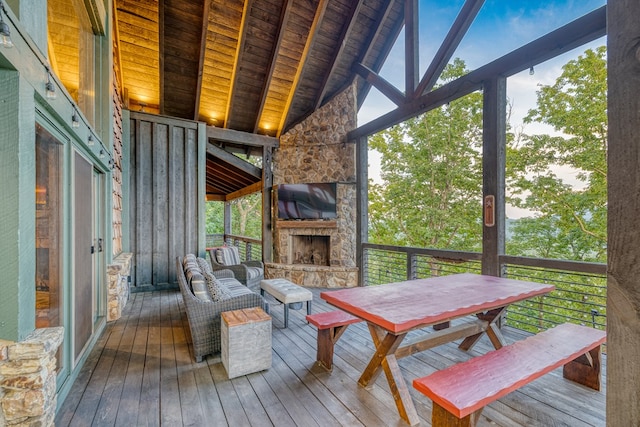 sunroom / solarium featuring a healthy amount of sunlight, an outdoor stone fireplace, and beamed ceiling