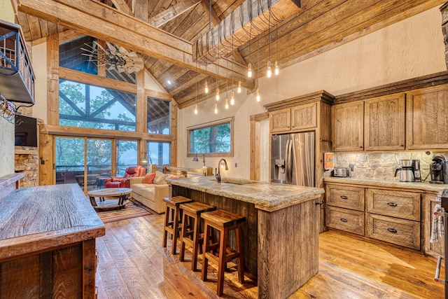 kitchen with stainless steel refrigerator with ice dispenser, light wood-style flooring, high vaulted ceiling, and beamed ceiling
