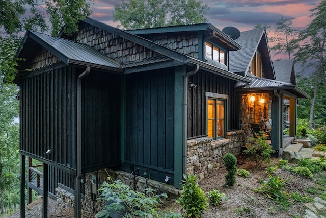 view of side of home featuring metal roof and stone siding