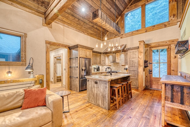 kitchen with open floor plan, wooden ceiling, stainless steel fridge with ice dispenser, a sink, and light wood-style flooring